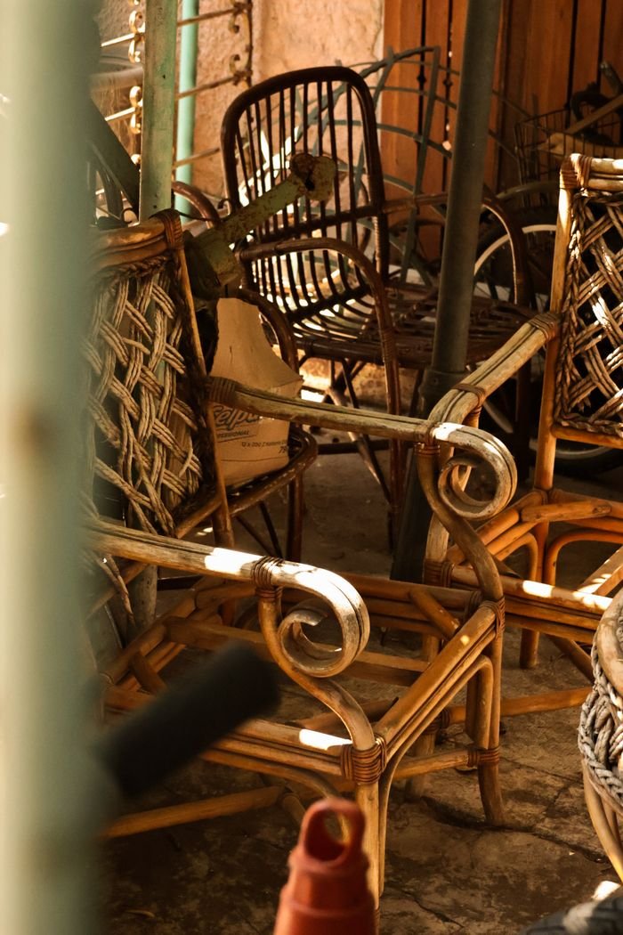 Sunlit wicker chairs in a rustic antique setting, showcasing warm tones and textures.